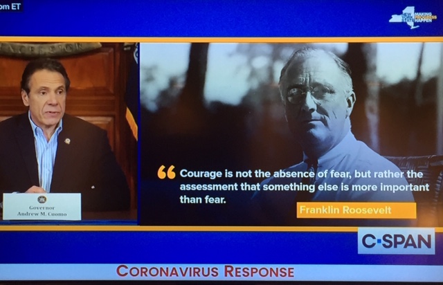 snapshot of a television screen depicting New York's Governor Andrew Cuomo speaking at a press briefing to the left; to the right, there's an image of Pres. Franklin Roosevelt and a quotation, attributed to Roosevelt: "Courage is not the absence of fear, but rather the assessment that something else is more important than fear."